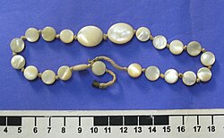 A necklace made out of strung mother of pearl. Mother of pearl has been used for adornment for thousands of years due to its lustrous appearance and finish.
